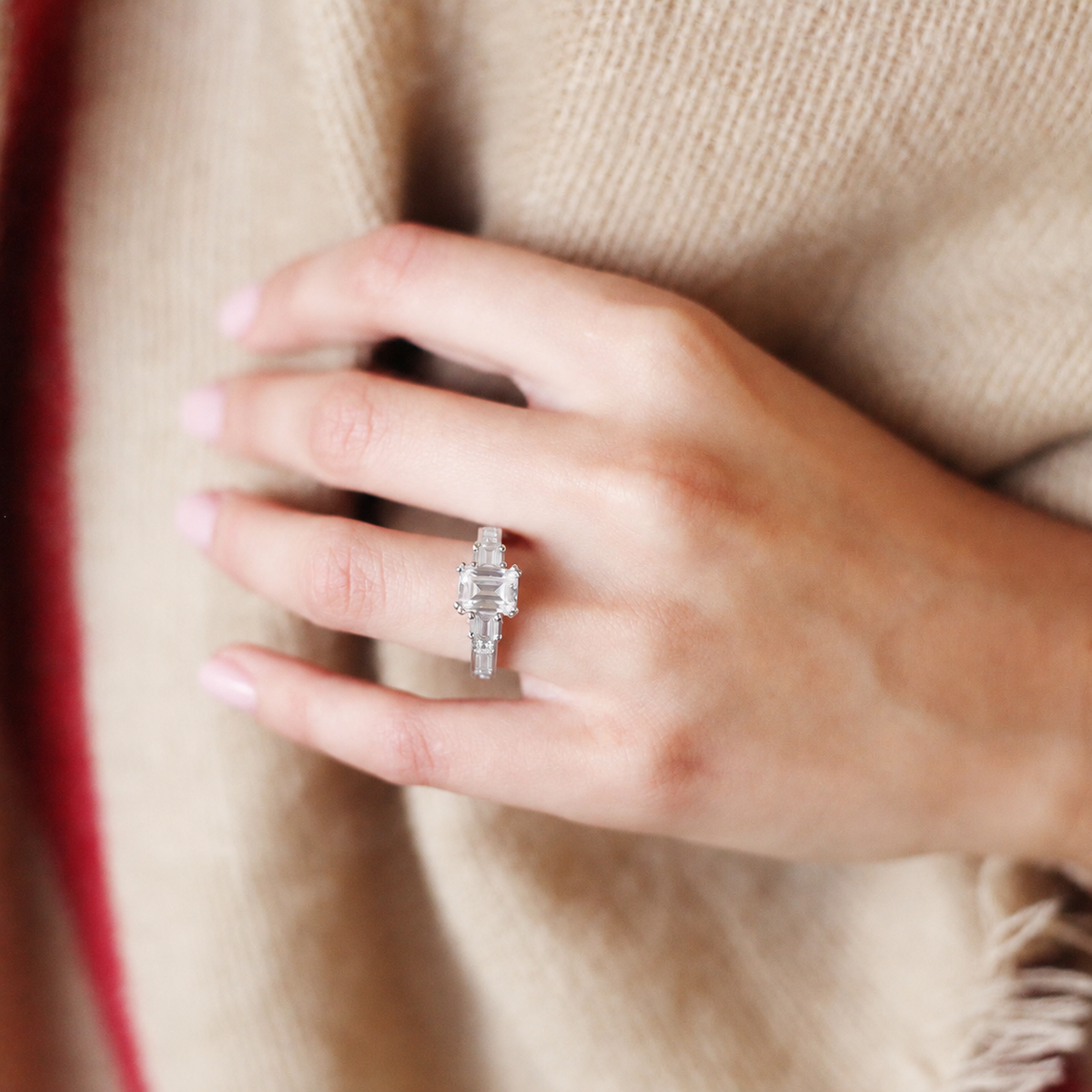 Worn on hand, showing deco three-stone engraved baguette diamond engagement ring.