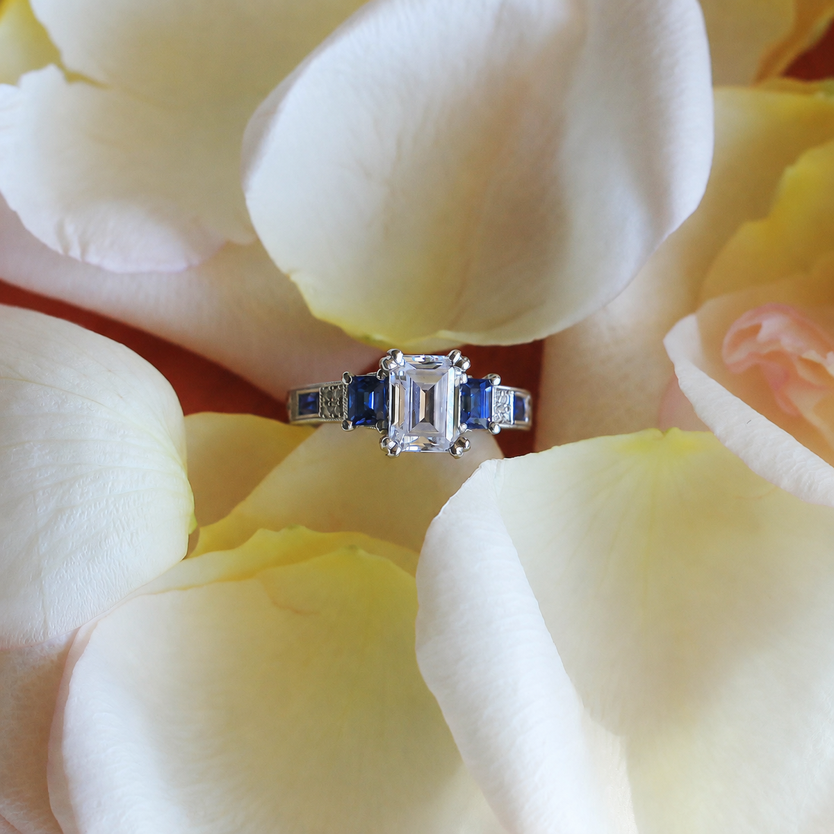 View of deco three-stone engraved sapphire baguette diamond engagement ring.